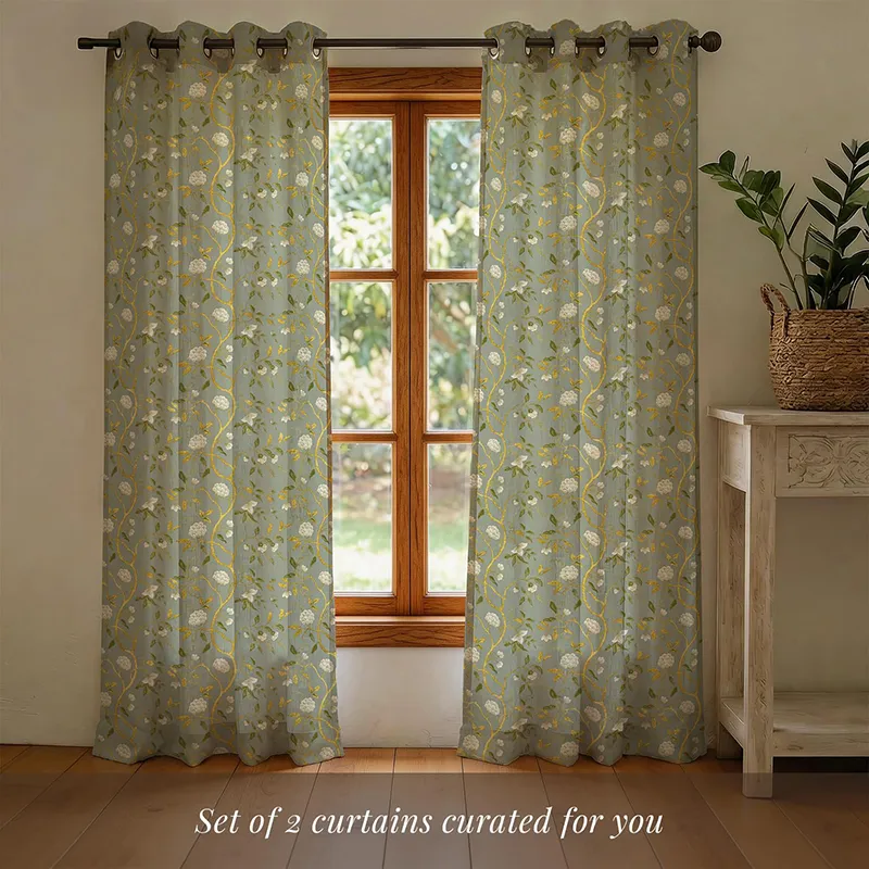 Set of two sage green floral curtains hanging on a window rod