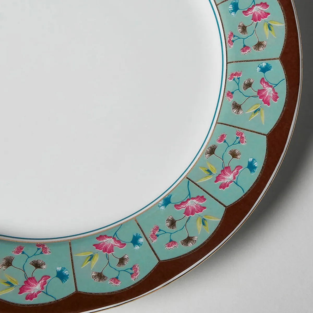 Detailed view of pink and blue flowers on the decorative plate rim.