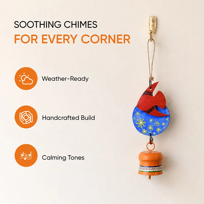 Fish-shaped windchime hanging on a wall with orange bell below