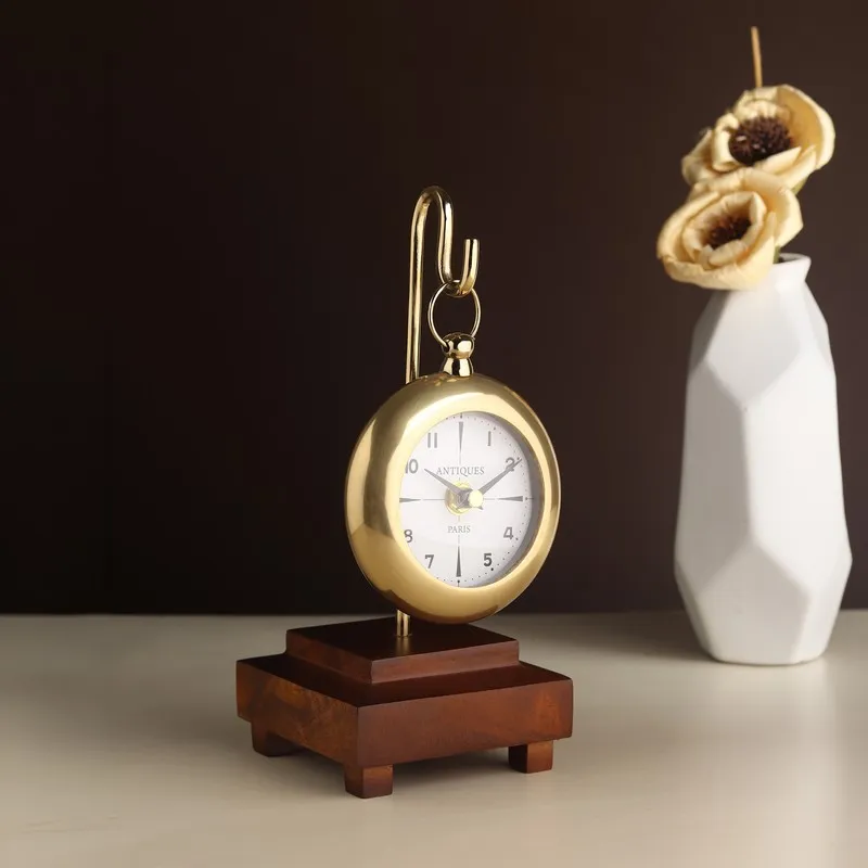 Angled view of a gold suspended table clock with wooden base