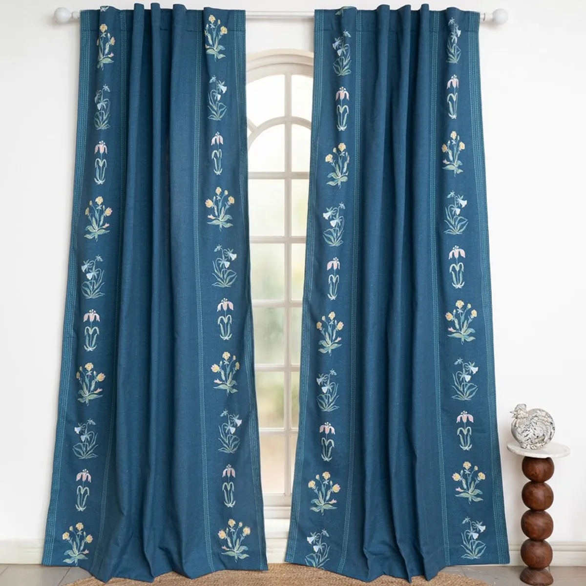 Pair of blue floral curtains displayed across a bright arched window