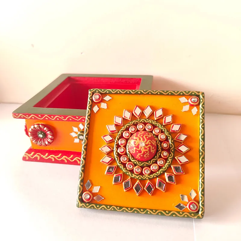 Open multicolour square box with decorated lid placed beside it