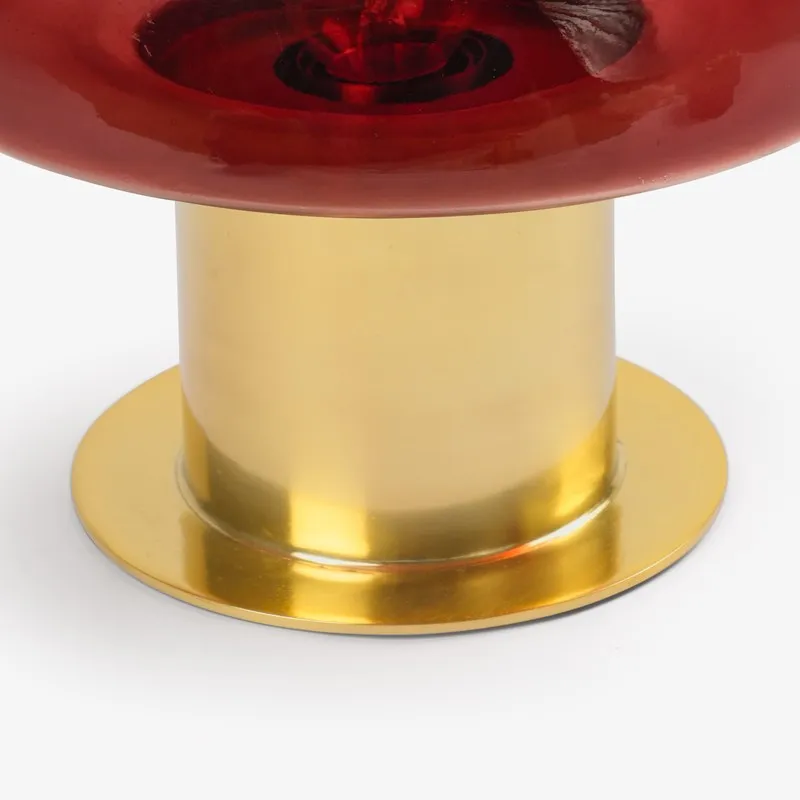 Close-up of the red glass shade edge and polished gold lamp base