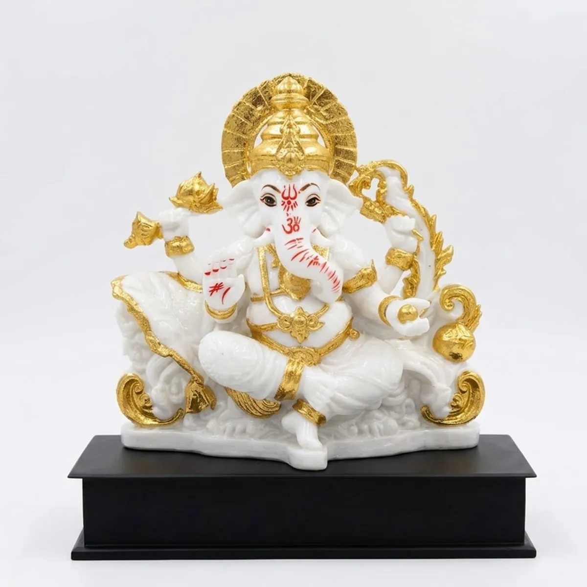 White and gold Ganesha idol shown against a plain light background