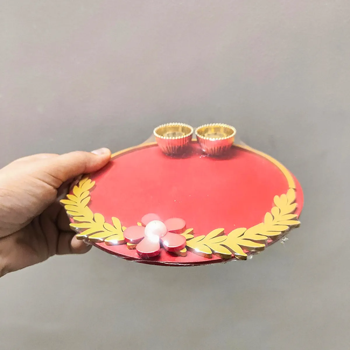 Side view of maroon round pooja thali with floral accent and two bowls