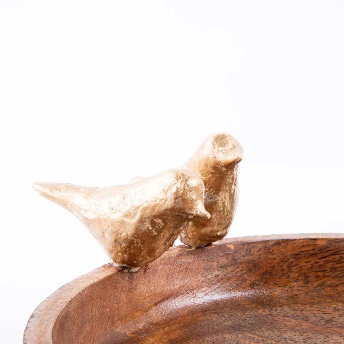Close-up of two gold bird figures attached to the bowl rim