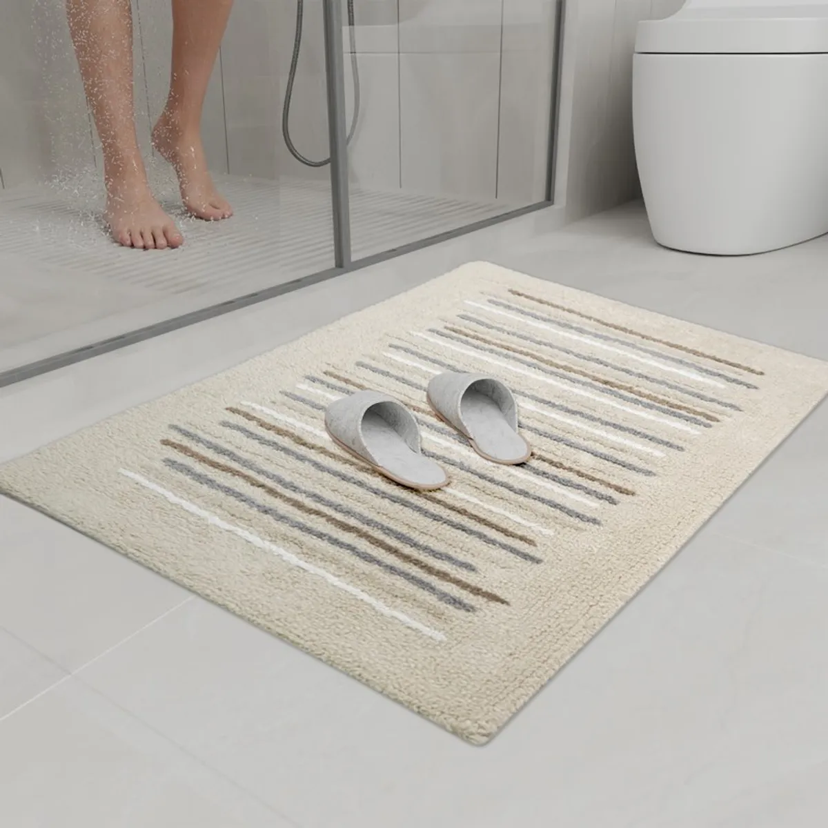 Beige striped bath mat placed beside a shower in a modern bathroom.