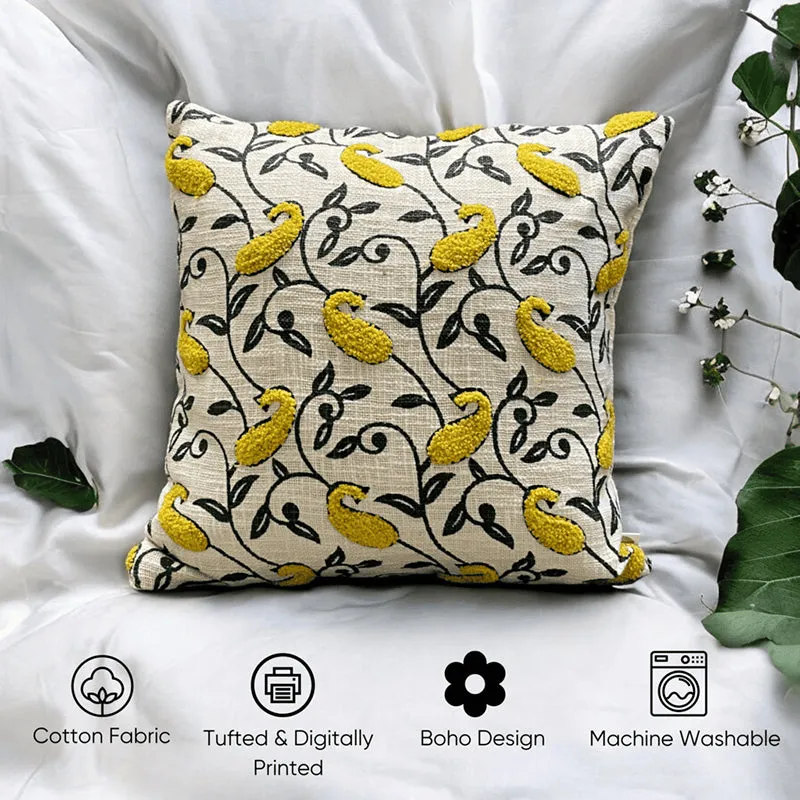 Yellow paisley cushion cover styled on white fabric with green leaves