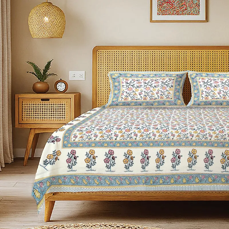 Blue and off-white floral bedsheet with matching pillow covers on a wooden bed