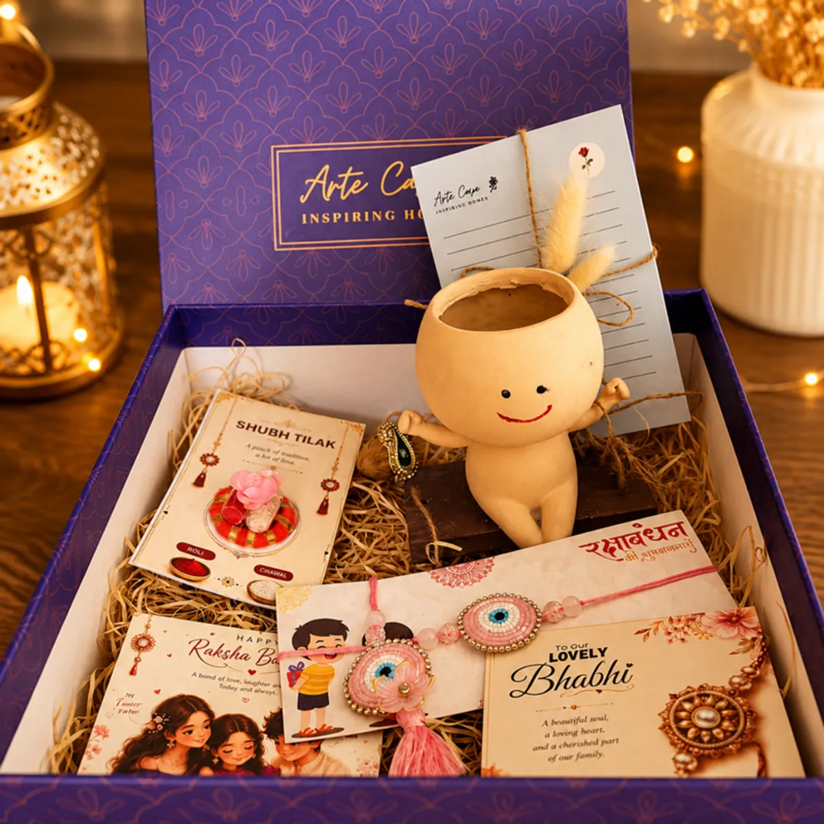 Open blue patterned Rakhi hamper styled with a smiling planter, cards and Rakhis