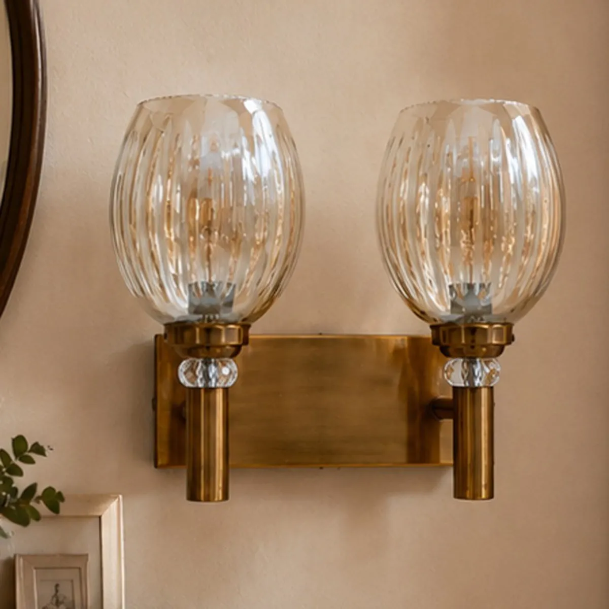 Front view of a gold wall lamp with two clear ribbed glass globes