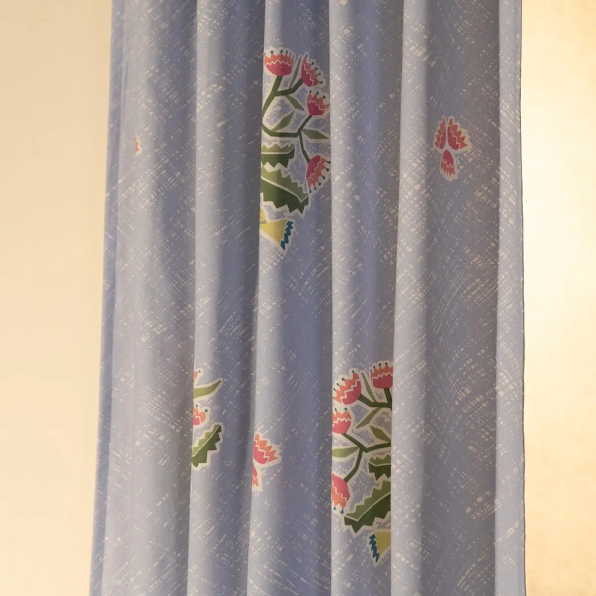 Close-up of light blue curtain fabric with floral motifs and texture