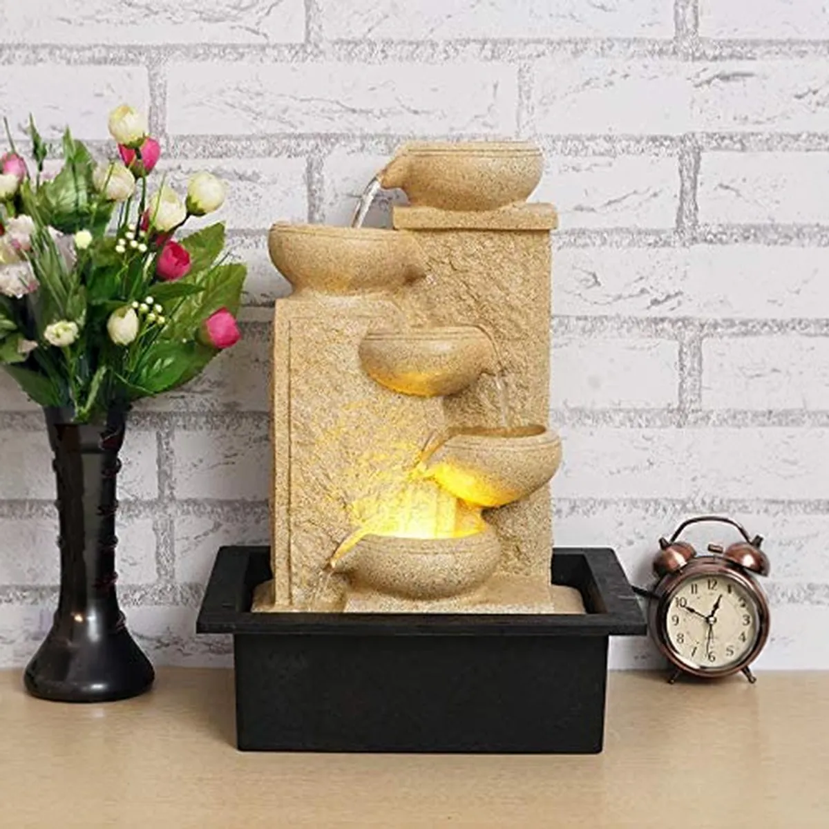 Ivory LED tabletop fountain with cascading bowls displayed on a table against a brick wall