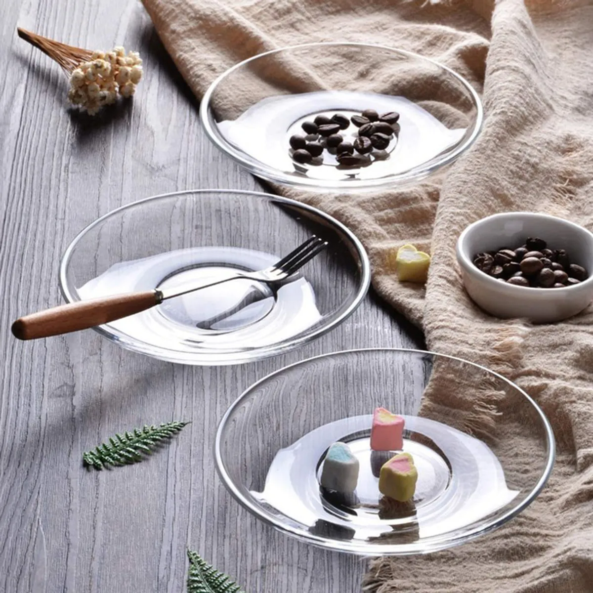 Three clear glass saucers styled on a wooden table with small bites