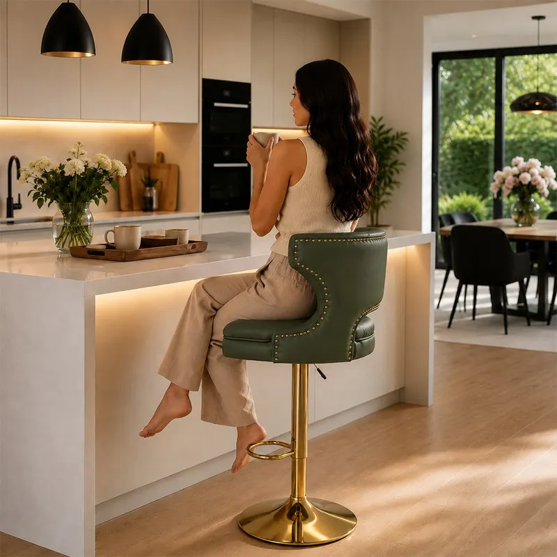 Side view of a green swivel bar stool with curved back, gold-toned base and footrest