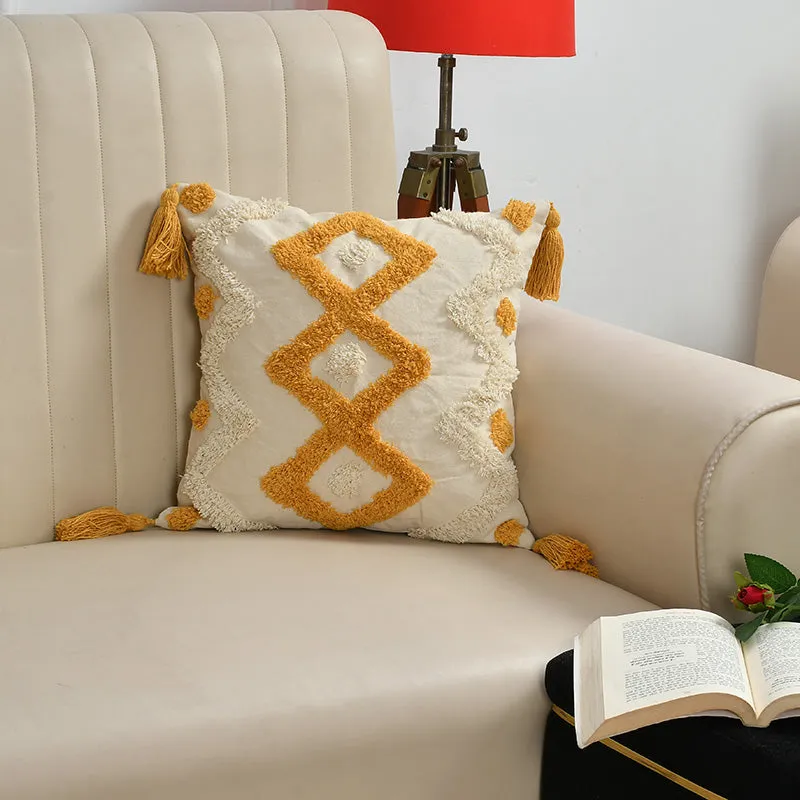 Single cream cushion cover with mustard geometric tufting and corner tassels on an armchair