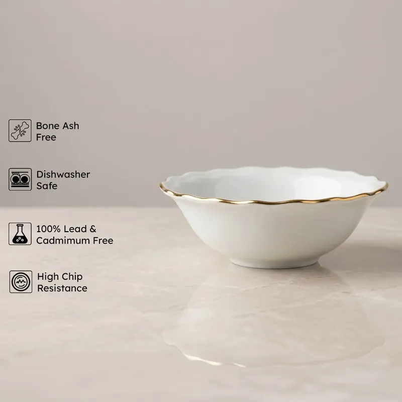 White serving bowl with gold rim shown on a tabletop