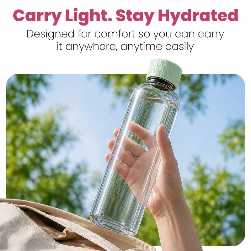 Transparent glass water bottle held outdoors against a leafy background.