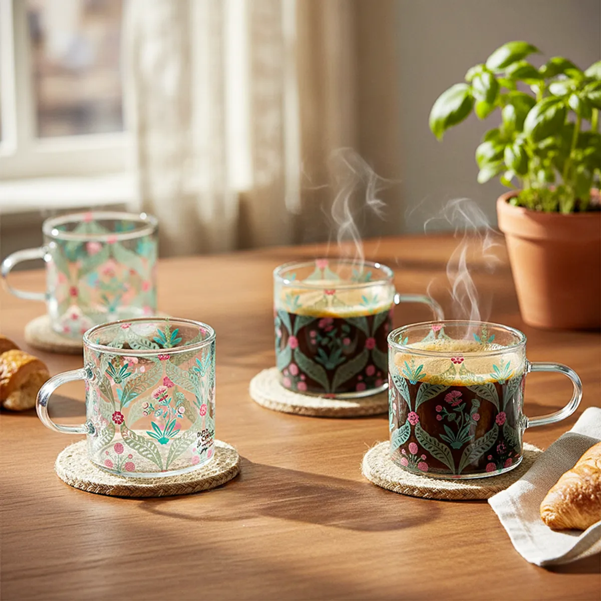 Set of four transparent glass mugs with floral prints on a wooden table