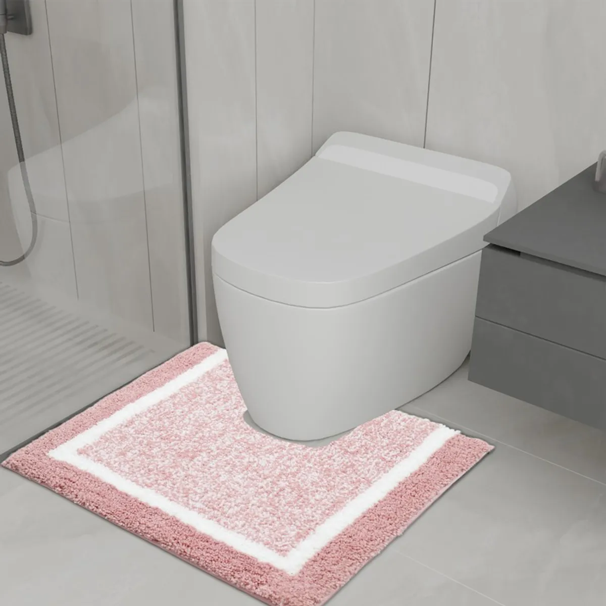 Pink and white geometric bath mat placed in a modern bathroom.