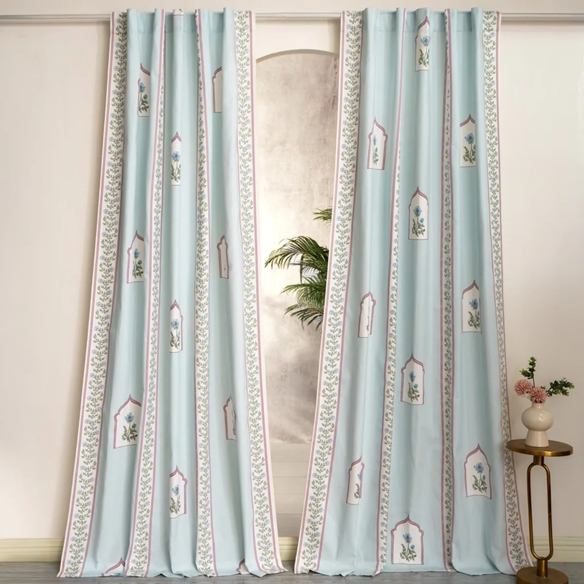 Pair of light blue floral curtains hanging on a large window