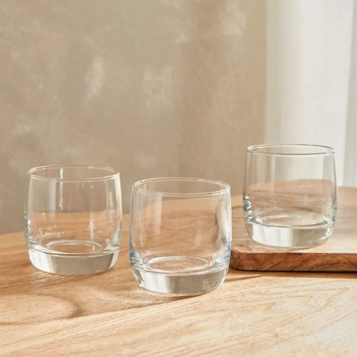 Three transparent drinking glasses displayed on a wooden table