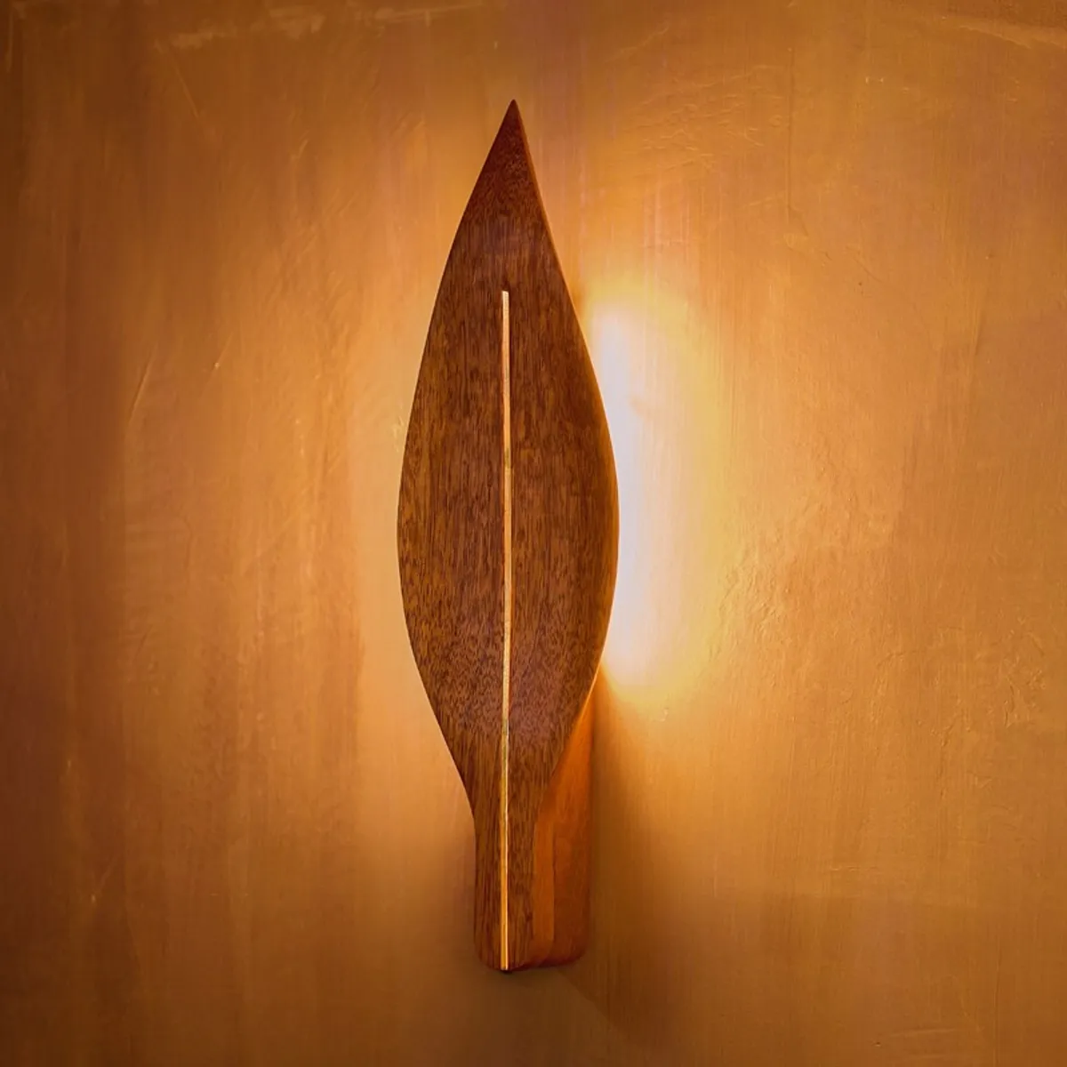 Front view of a leaf-shaped brown wall lamp with warm backlit glow