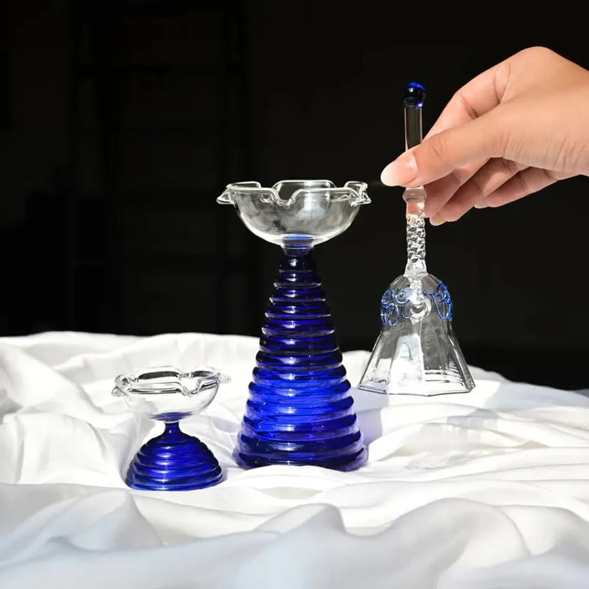 Three-piece blue and transparent glass pooja set displayed against a white backdrop