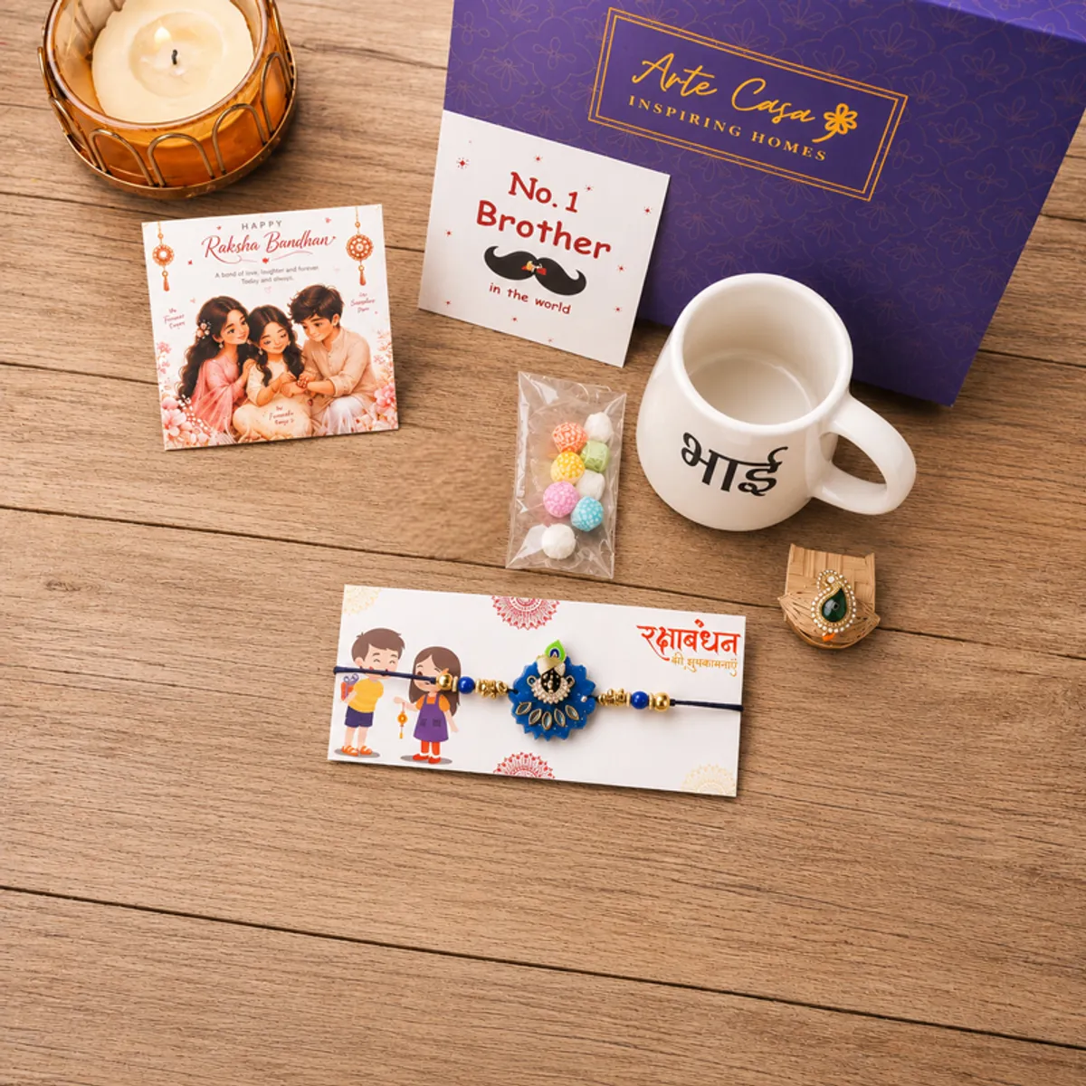 Rakhi hamper arranged on a wooden surface with gift box, mug, cards and colourful sweets
