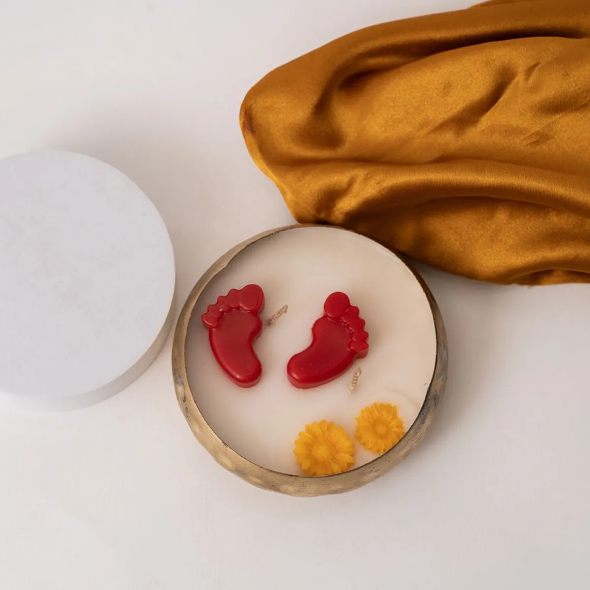 Top view of a round candle featuring red footsteps and yellow flower details.