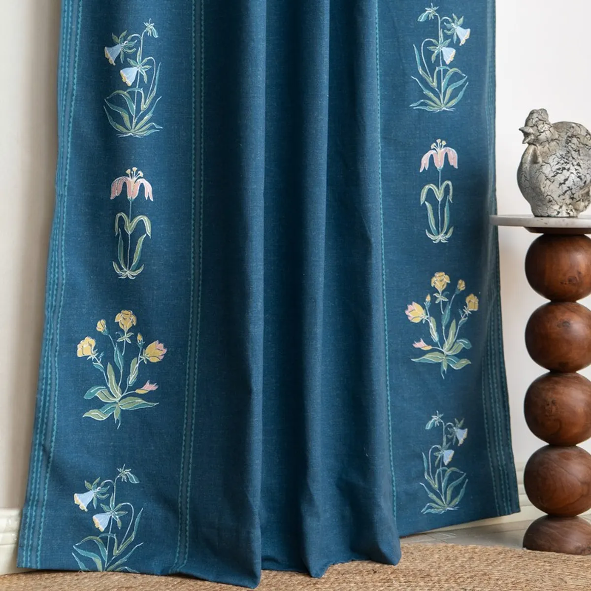 Blue floral curtain hanging beside a sculptural wooden side table