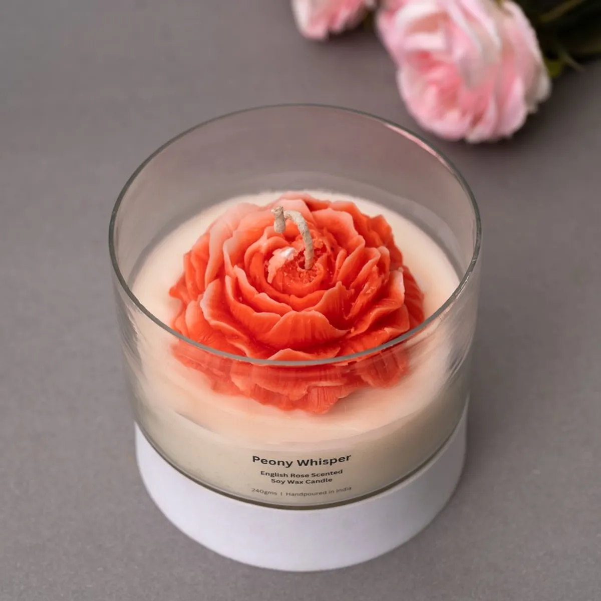 Angled view of a red rose-shaped candle in a clear glass container