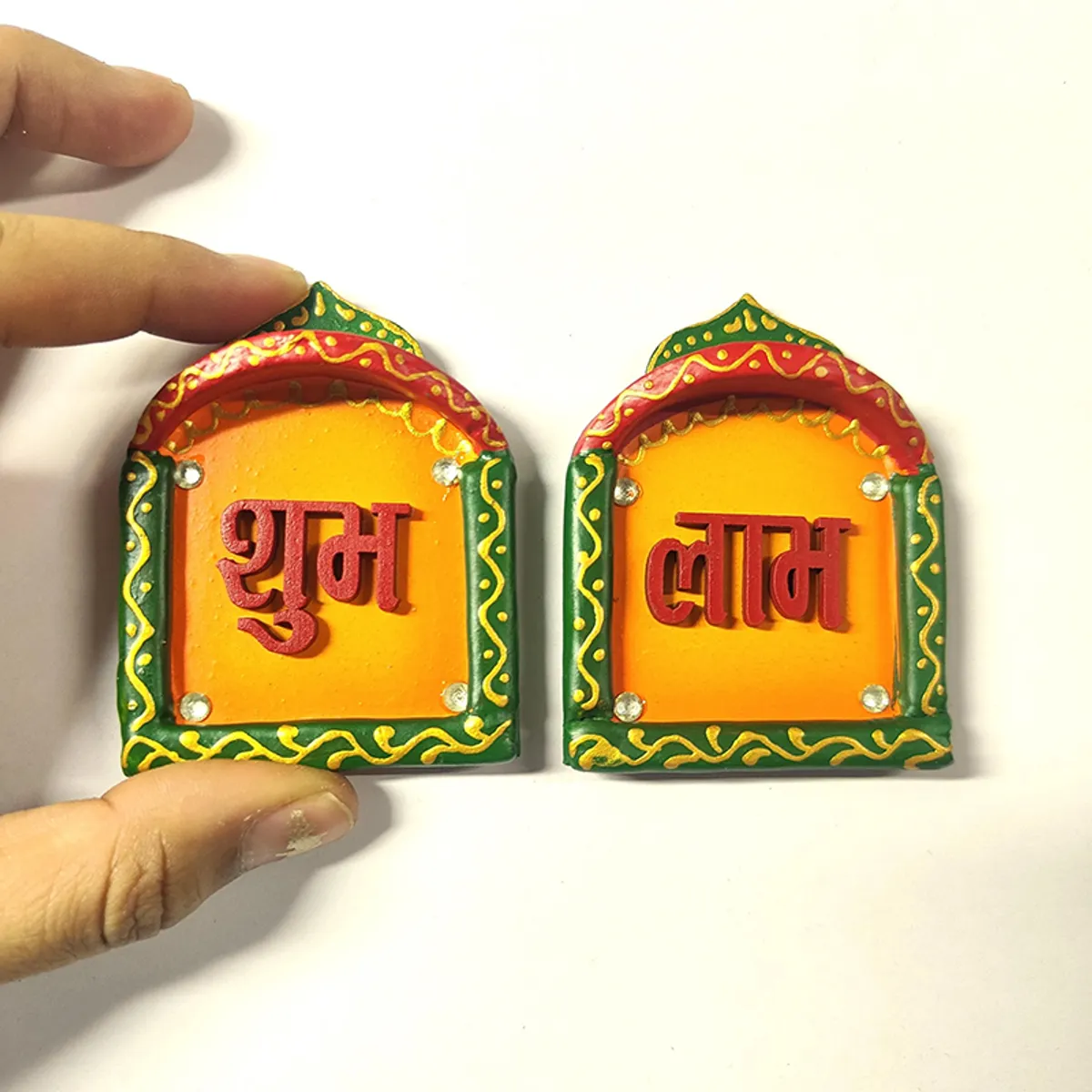 Hand holding one of the two Shubh Laabh wall accents