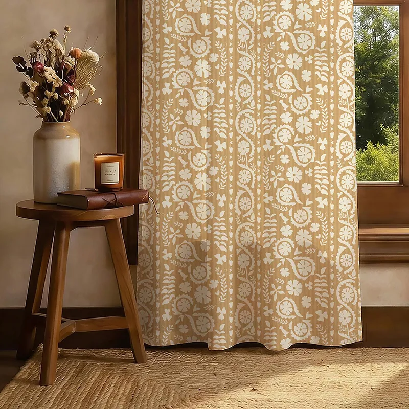 Beige printed curtain panel beside a wooden window and side table