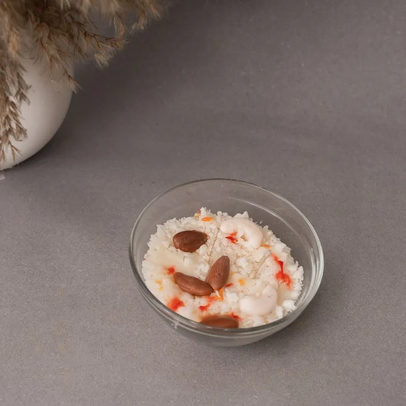 Top view of a white candle with brown and red accents in a clear glass bowl