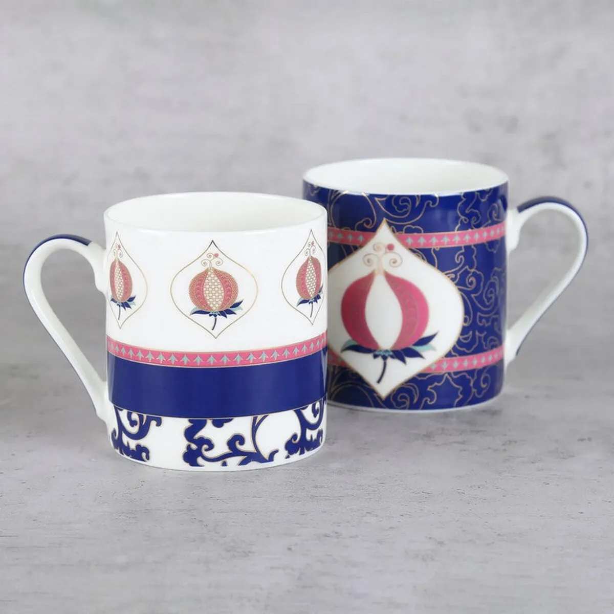 Close view of two glossy mugs with pink pomegranate motifs