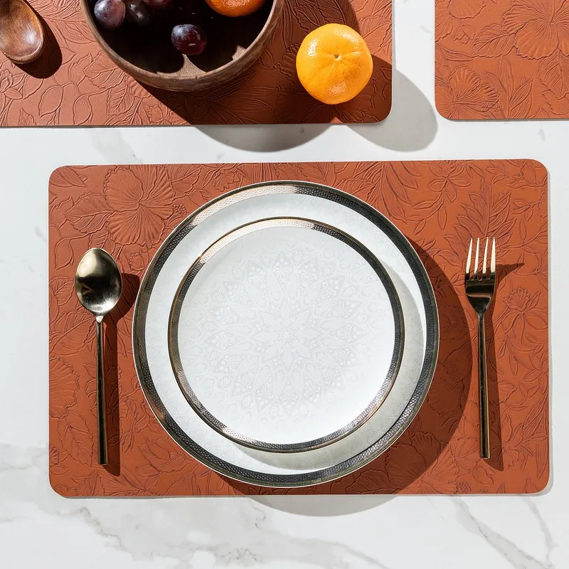 Single orange floral textured table mat with plate, spoon and fork