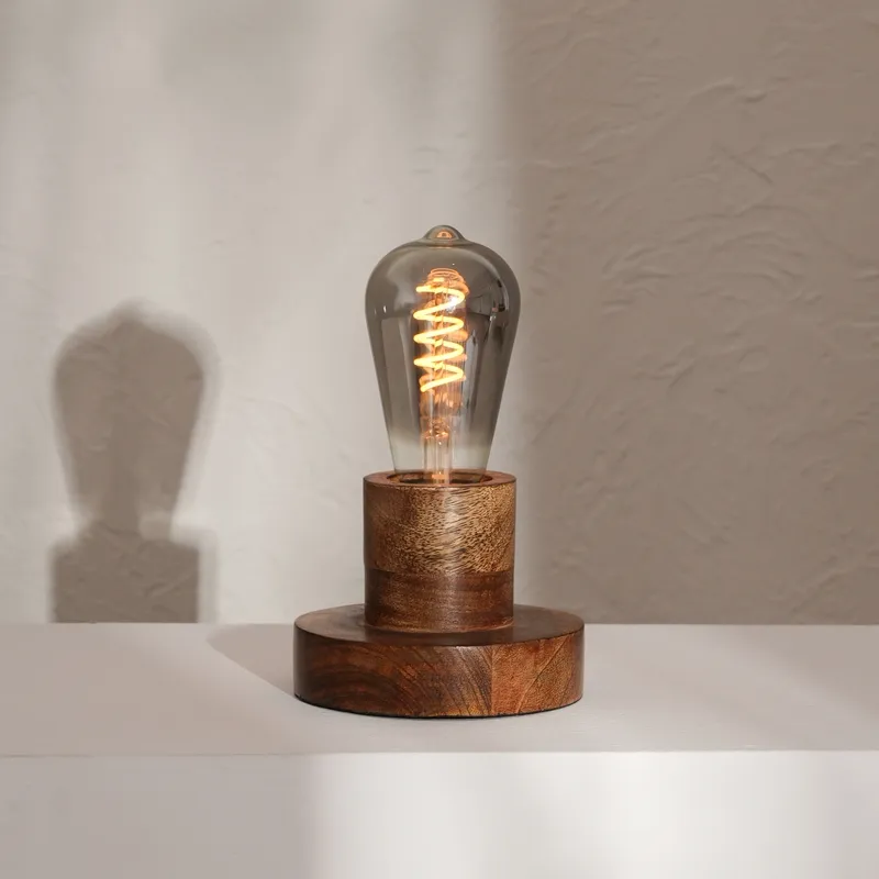 Wooden table lamp with smoked glass bulb on a white surface