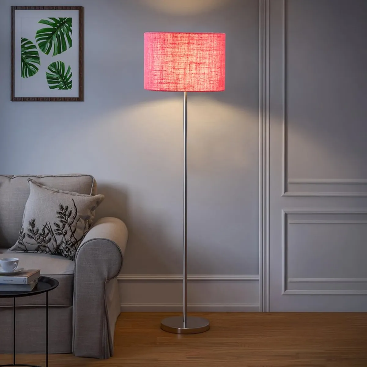Lit pink jute floor lamp beside a sofa in a neutral living room