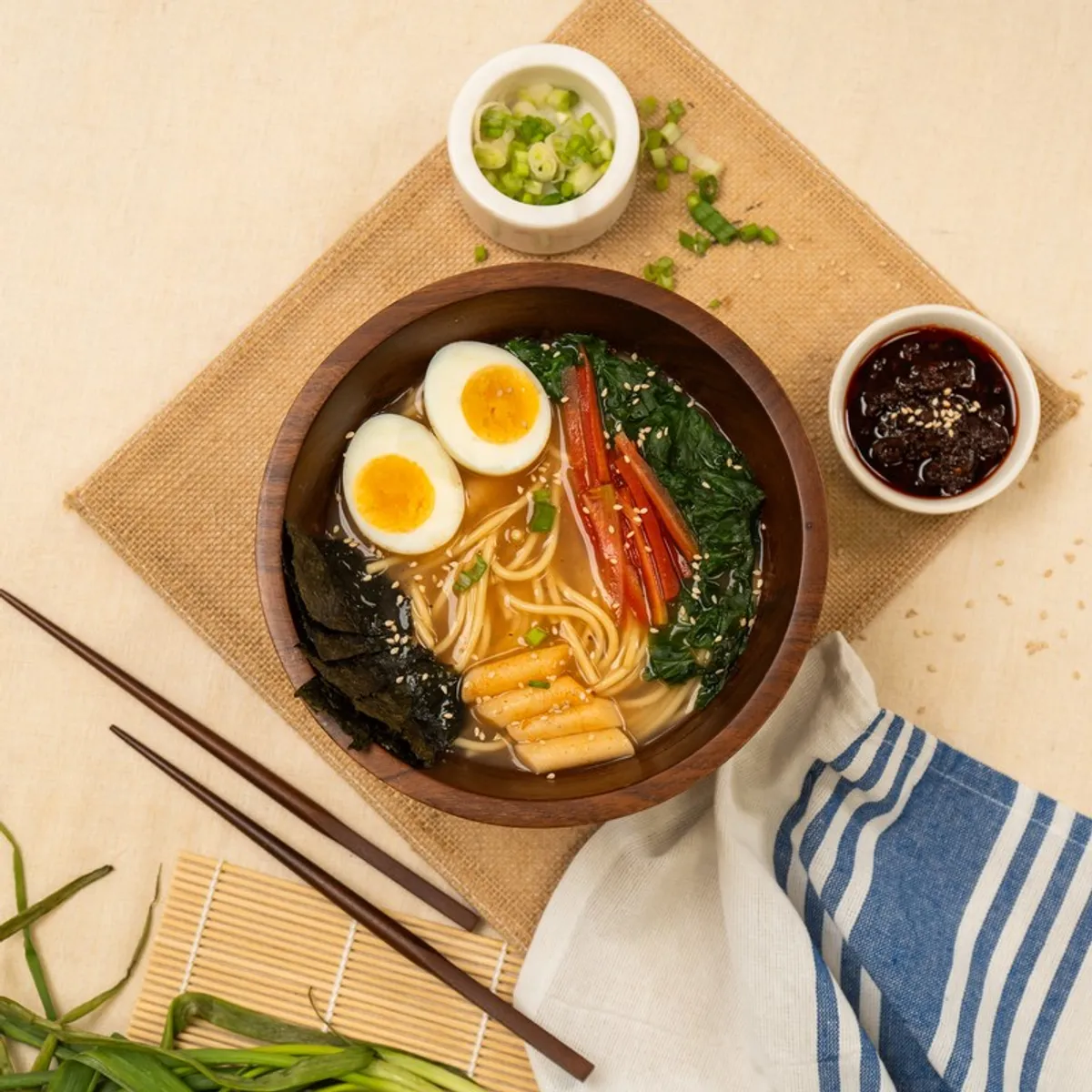 Top view of a brown wooden ramen bowl with chopsticks and garnishes