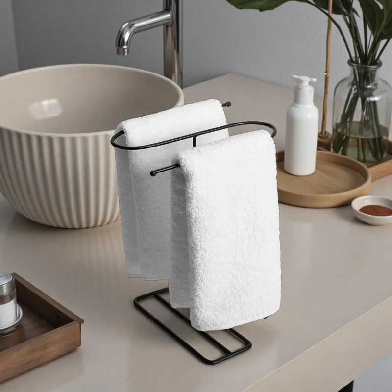 Black towel hanger with white towels styled beside a basin and bathroom accessories