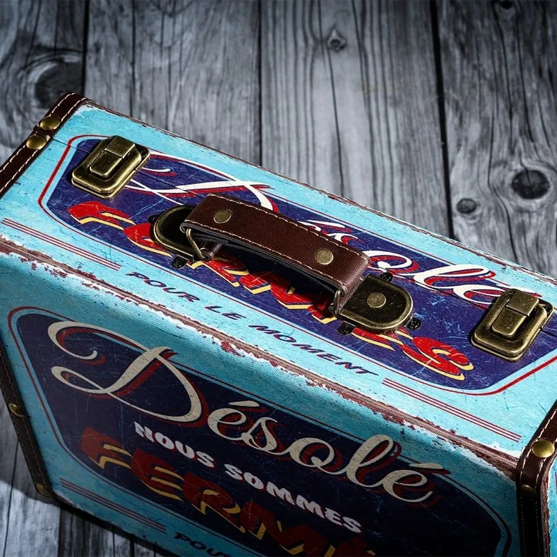 Close-up of a blue vintage storage trunk with printed artwork and brown handle