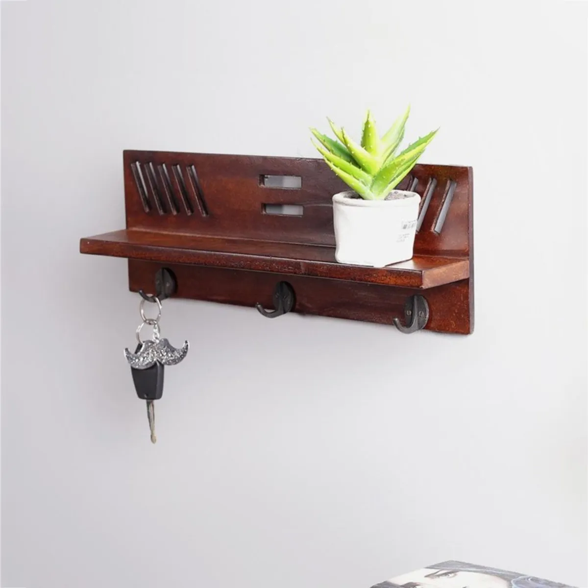 Angled view of wooden wall shelf with hooks and cut-out back panel