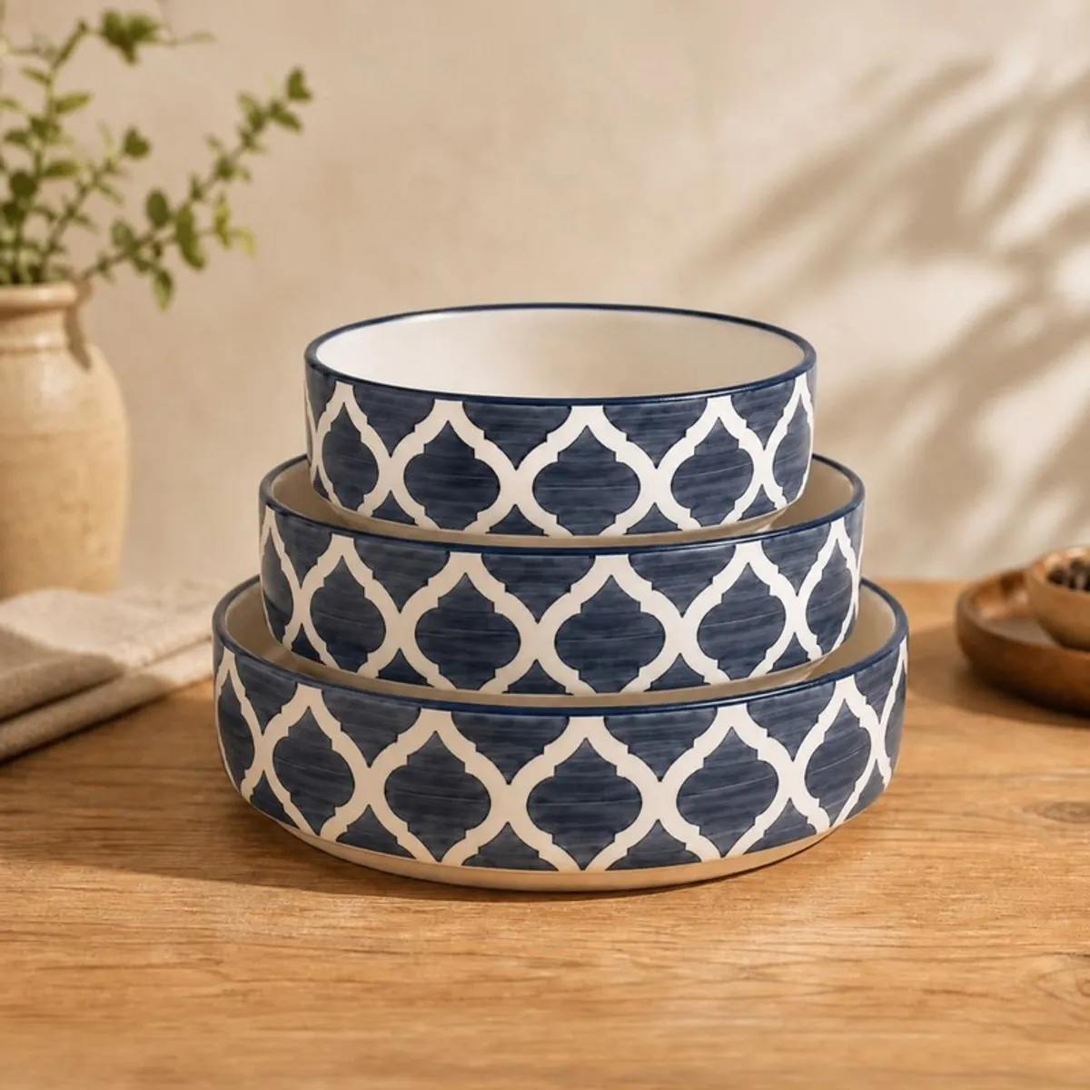 Three blue and white patterned bowls stacked by size on a wooden table.
