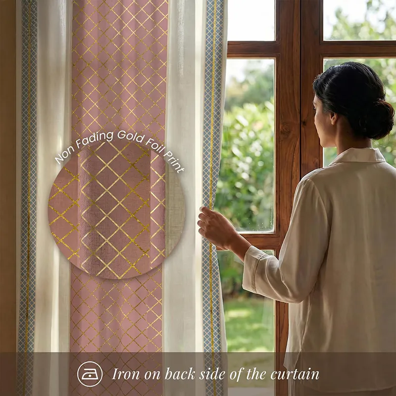Pink curtain with gold geometric foil print beside a sunlit window