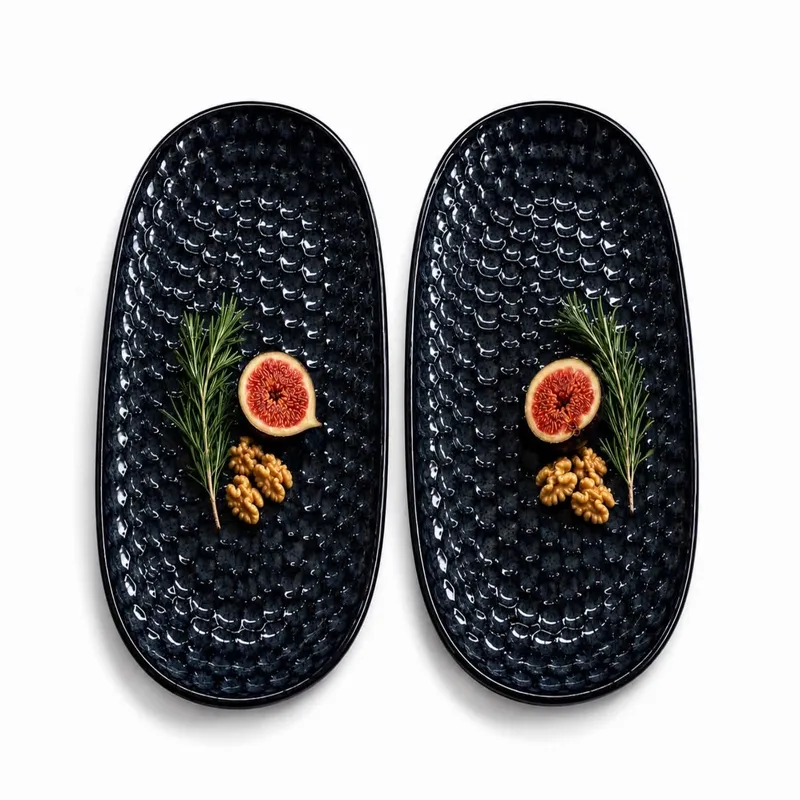 Two dark blue oval platters with textured surfaces and simple food garnishes
