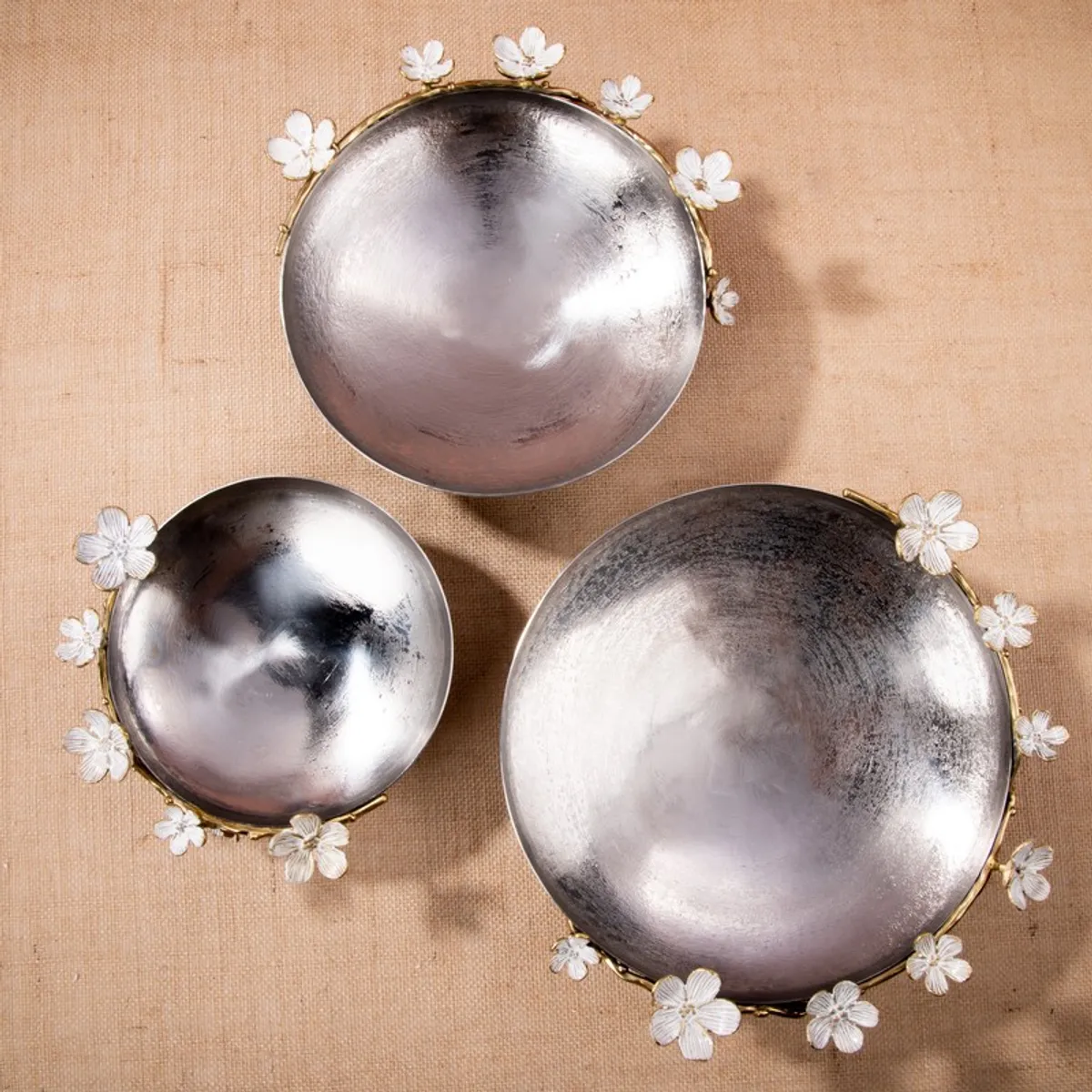 Top view of three differently sized silver bowls with floral borders