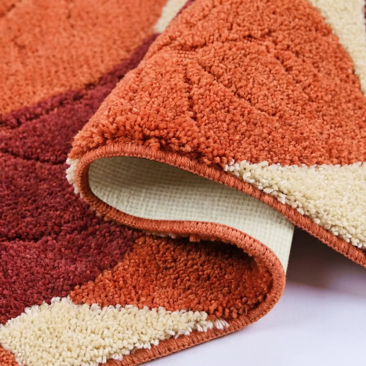 Close-up showing the plush pile and rolled edge of the rust bath mat