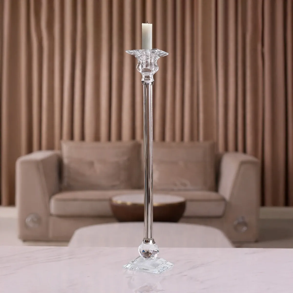 Tall clear crystal candle holder with a white candle in a living room