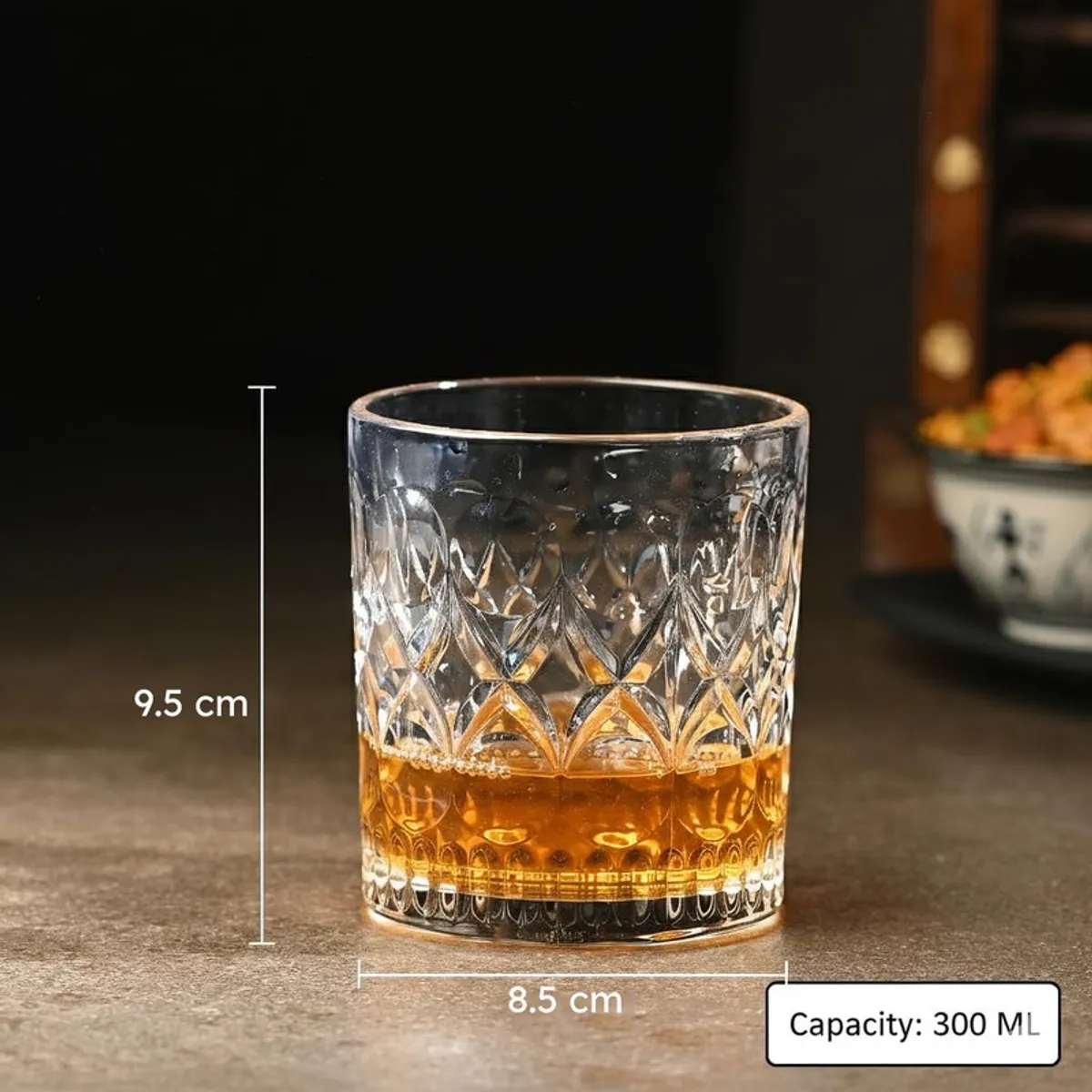 Clear textured whiskey glass with amber drink shown against a dark background